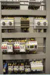 A programmable logic control panel with rows of breakers and relays